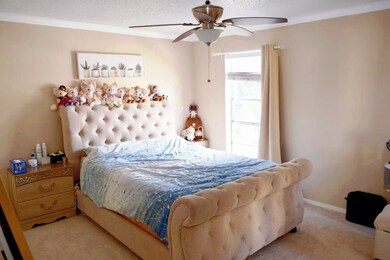Bedroom with crown molding, carpet, a ceiling fan, and a textured ceiling