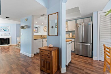 Kitchen featuring white appliances, dark wood-style flooring, recessed lighting, and a fireplace with raised hearth