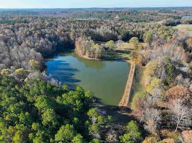Aerial view of property and surrounding area with a heavily wooded area and a nearby body of water