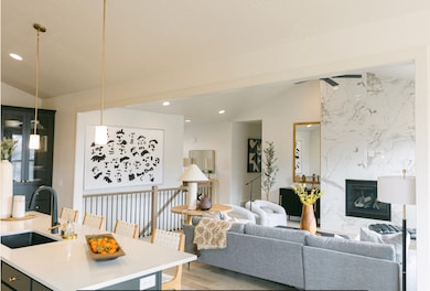 Living area featuring vaulted ceiling, light wood-style floors, a fireplace, and recessed lighting