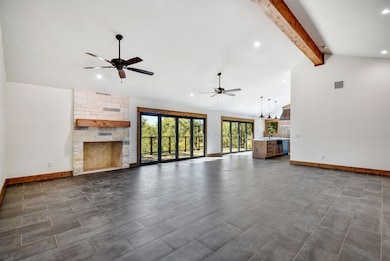 Unfurnished living room with recessed lighting, a ceiling fan, high vaulted ceiling, beamed ceiling, and a stone fireplace