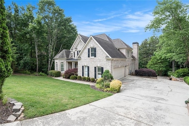 View of front facade with concrete driveway, brick siding, a front lawn, a chimney, and a shingled roof