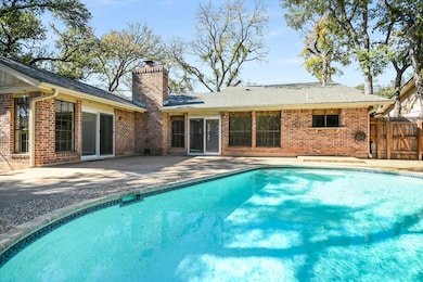 Back of house with a patio, brick siding, a chimney, and roof with shingles