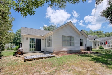 Rear view of house featuring a deck, a lawn, and roof with shingles