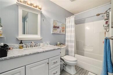 Updated primary bathroom features tall vanity, newer flooring, and a shower over the tub.
