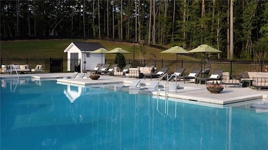 Community pool with a patio area, an outdoor structure, and fence