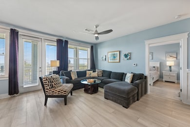 The living room is filled with natural light and offers unobstructed views of the pool and bay through expansive windows.