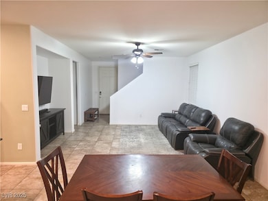 Living area featuring light tile patterned floors and a ceiling fan