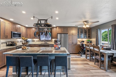 Kitchen with decorative backsplash, a kitchen bar, stainless steel appliances, light wood finished floors, and a kitchen island