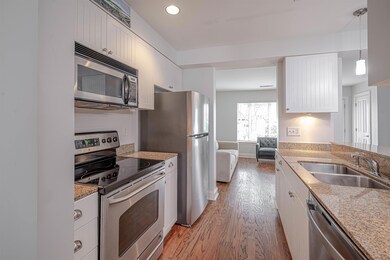 Kitchen with appliances with stainless steel finishes, a sink, light wood-type flooring, white cabinets, and recessed lighting
