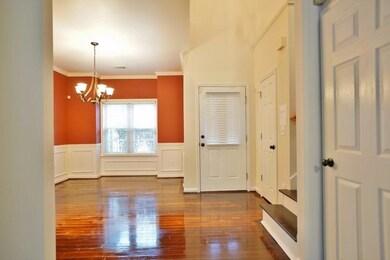 Entryway featuring hardwood / wood-style floors, crown molding, wainscoting, a decorative wall, and a chandelier