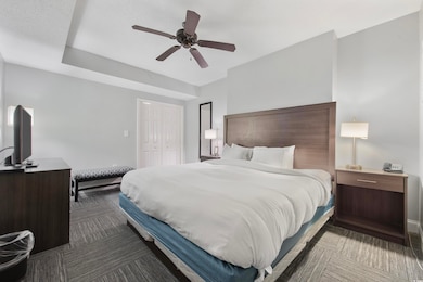 Bedroom featuring a ceiling fan, a closet, and dark colored carpet