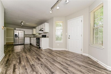 Kitchen featuring appliances with stainless steel finishes, dark wood finished floors, white cabinets, rail lighting, and a textured ceiling