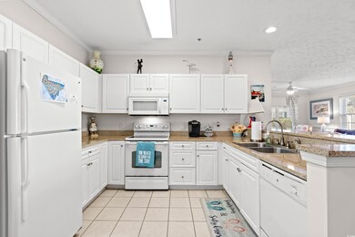 Kitchen with sink, white cabinets, white appliances, and kitchen peninsula