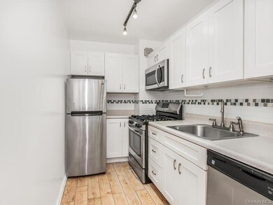Kitchen with stainless steel appliances, light countertops, tasteful backsplash, and white cabinetry