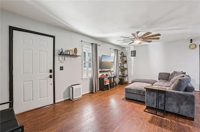 Living room featuring dark wood-style flooring and a ceiling fan