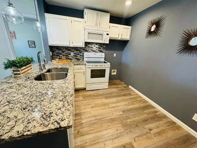Kitchen with white appliances, light stone counte