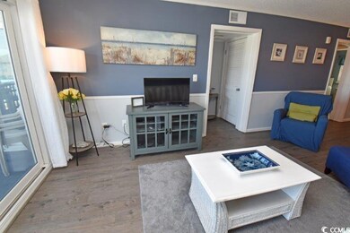 Living room with wood finished floors, crown molding, and baseboards