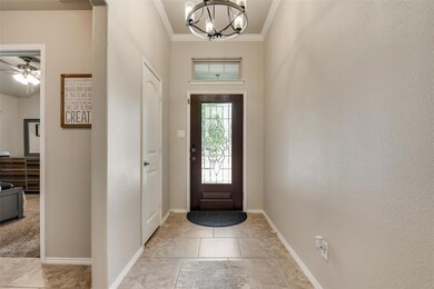 Entryway with crown molding, light tile floors, and light fixture