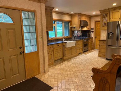 Kitchen featuring stainless steel appliances, wall chimney exhaust hood, crown molding, dark countertops, and decorative backsplash