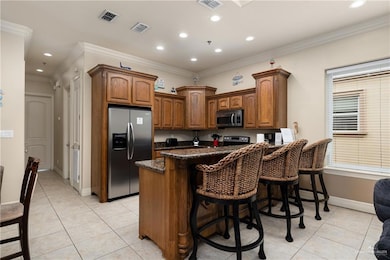 Kitchen featuring stainless steel appliances, light tile patterned floors, a kitchen breakfast bar, ornamental molding, and recessed lighting