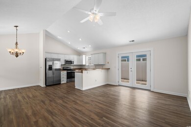 Kitchen featuring stainless steel appliances, a peninsula, open floor plan, ceiling fan, and dark wood-style flooring
