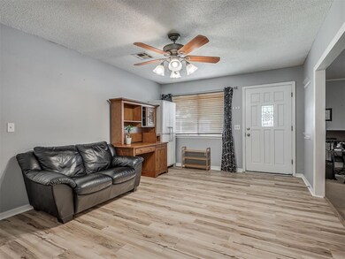 Living area with ceiling fan, light wood-style floors, a textured ceiling, and baseboards