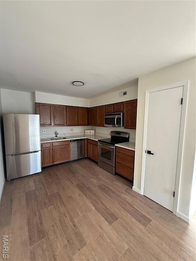 Kitchen featuring appliances with stainless steel finishes, light countertops, and light wood-style flooring