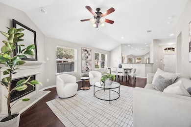 With soaring ceilings and wide-open sight lines, this living and dining area flows effortlessly—anchored by a classic fireplace and surrounded by windows that fill the home with natural light.