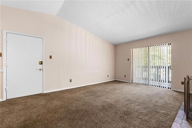 Unfurnished room with vaulted ceiling, carpet, and a textured ceiling