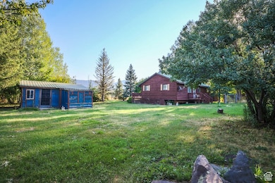 View of grassy yard featuring an outbuilding and a deck