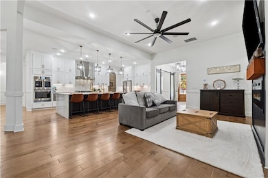 Living room with a ceiling fan, a chandelier, light wood-style flooring, and recessed lighting
