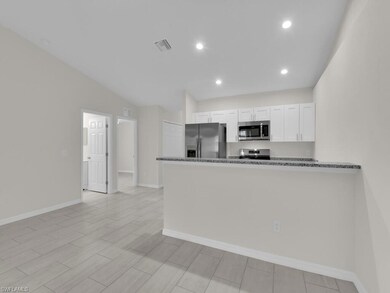 Kitchen with stainless steel appliances, white cabinets, baseboards, dark stone counters, and a peninsula