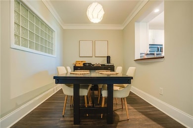 Dining room with crown molding and dark wood-type flooring