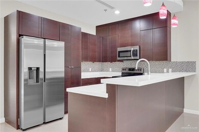 Kitchen featuring appliances with stainless steel finishes, a peninsula, light countertops, backsplash, and decorative light fixtures