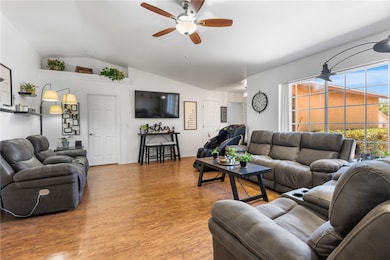 Living room featuring lofted ceiling, light wood-type flooring, and ceiling fan