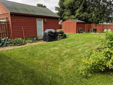 Fenced backyard facing garage and shed.