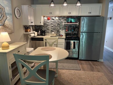 Kitchen featuring appliances with stainless steel finishes, a sink, wood finished floors, white cabinetry, and backsplash