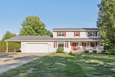View of front of property featuring a porch, driveway, an attached garage, and a front lawn