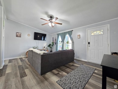 Living area with wood finished floors, crown molding, and ceiling fan