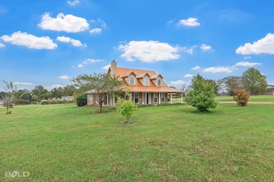 View of front of home with a front yard, a chimney, covered porch, and a metal roof