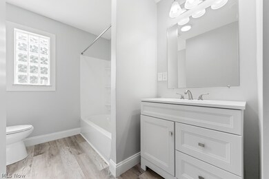 Full bathroom featuring washtub / shower combination, hardwood / wood-style flooring, toilet, and vanity