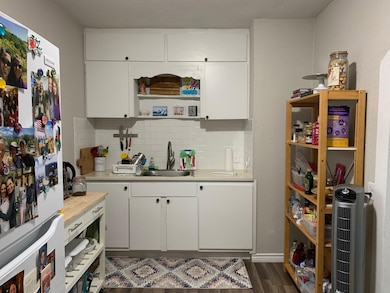 Kitchen with freestanding refrigerator, open shelves, white cabinets, tasteful backsplash, and dark wood finished floors