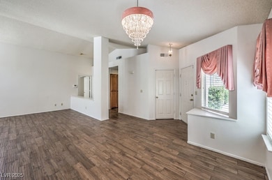 Empty room with a chandelier, dark wood-style floo