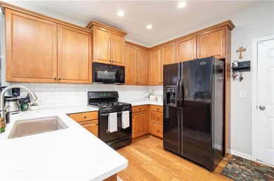 Kitchen with white and light gray veined quartz countertops, white subway tile backsplash, wood stained cabinets and recessed lighting. Pantry is next to the laundry room. Garage door access from kitchen.