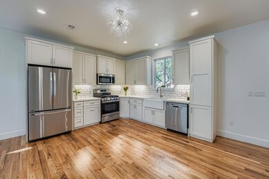 Kitchen with stainless steel appliances, white cabinetry, light wood-style floors, decorative backsplash, and recessed lighting