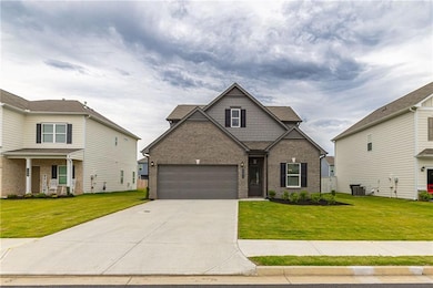 Craftsman-style house with brick siding, concrete driveway, a front lawn, and central AC unit