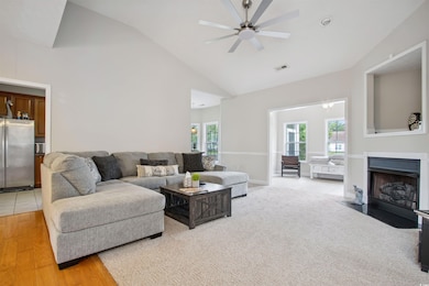 Living room featuring ceiling fan, high vaulted ceiling, a fireplace with flush hearth, and light wood-type flooring