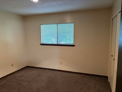 Spare room featuring dark colored carpet and baseb