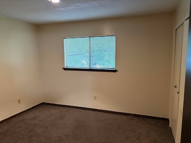 Spare room featuring dark colored carpet and baseb
